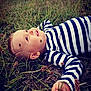 Lorenzo a rejoint le concours — aidez-le/la à gagner de superbes lots ! baby, child, grass, outdoor, nature, striped_shirt, lying_down, happy, curious, face, hand, greenery, field, young_child, portrait, casual_clothing, daylight, relaxed, smiling, small_flowers