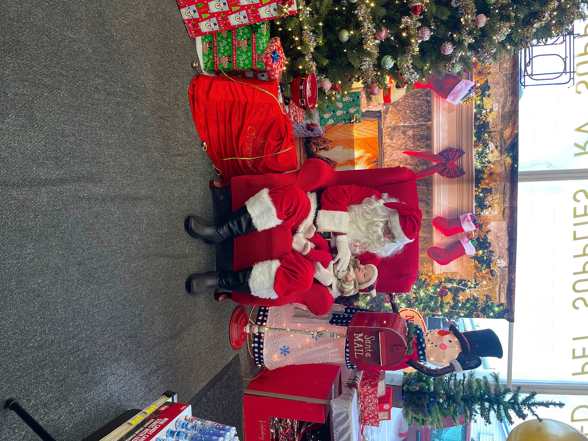 Betty is registered to the contest to win money with this photo: carmine, christmas, christmas_decoration, christmas_eve, christmas_ornament, christmas_tree, decoration, event, headwear, holiday, holiday_ornament, ornament, person, plant, red, retail, santa_claus, shelf, souvenir, tradition