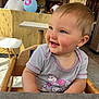 baby, child, smile, high_chair, indoor, shirt, cartoon, balloon, wooden, table, person, happy, face, cute, toddler, blue_eyes, short_hair, casual_clothing, daylight, restaurant