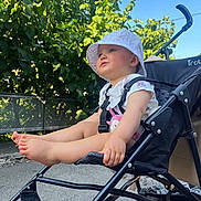 Hanaé a rejoint le concours — aidez-le/la à gagner de superbes lots ! baby, stroller, hat, outdoor, child, legs, feet, sunlight, greenery, blue_sky, sitting, cute, summer, infant, casual_clothing, daytime, nature, person, expression, relaxing