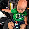 Xavier joined the competition — help win amazing prizes! baby, infant, child, car_seat, sleeping, eyes_closed, green_shirt, shorts, pacifier, toy, portrait, sitting, indoors, vehicle, automobile, safety_harness, bald, relaxed, close_up, family