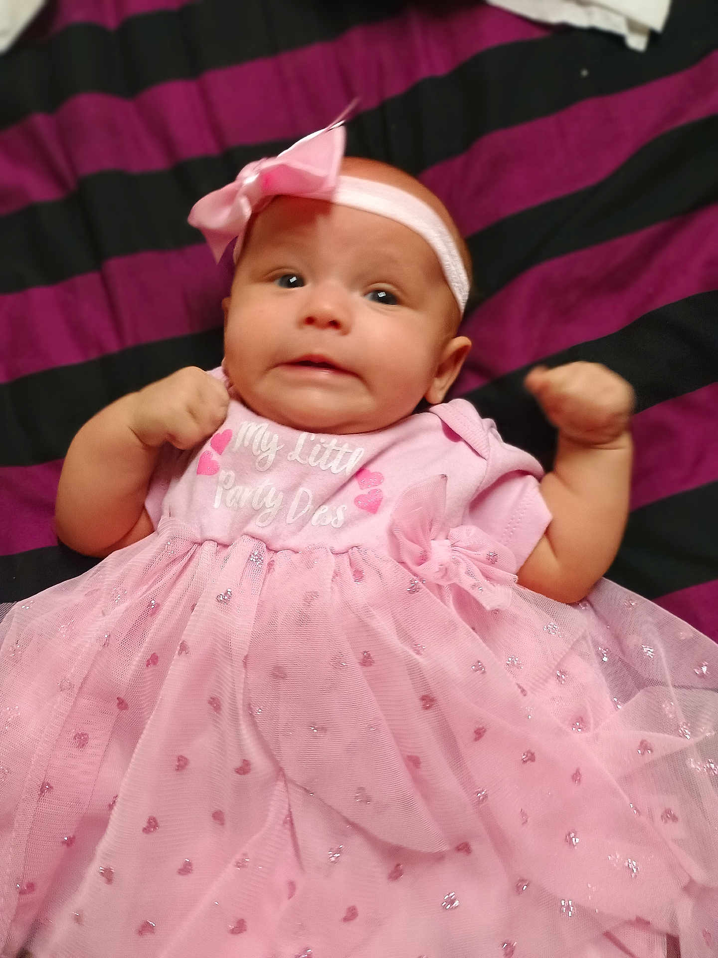 Justinalynn is registered to the contest to win money with this photo: adorable, baby, blanket, bow, child, clothing, cute, expression, fabric, fist, headband, indoors, infant, laying_down, newborn, person, pink_dress, portrait, small, striped_blanket