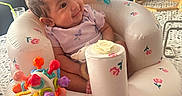 Reyna is registered to the contest to win money with this photo: baby, child, colorful_toy, cute, decor, face, happy, home, indoor, infant, inflatable_seat, patterned_floor, plant_pot, playful, purple_clothing, seated, small, smiling, toy, wooden_shelf