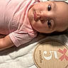 baby, infant, pink_clothing, lying_down, blanket, wooden_plaque, milestone, 5_months, cute, face, portrait, skin, head, cheeks, eyes, arm, newborn, baby_girl, soft_texture, indoor