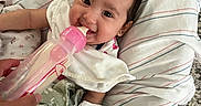 Reyna joined the competition — help win amazing prizes! baby, blanket, bottle, carpet, child, clothing, cushion, drinking, face, feeding, feet, hand, indoor, infant, person, portrait, smile, striped, toddler, young_child