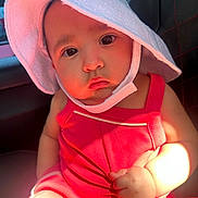 Reyna is registered to the contest to win money with this photo: baby, child, face, hat, sunhat, red_clothing, car_seat, infant, cute, portrait, skin, hand, arm, closeup, seat, child_in_car, sunlight, pout, expression, indoors