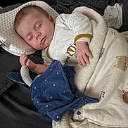 Thelyo a rejoint le concours — aidez-le/la à gagner de superbes lots ! baby, sleeping, blanket, plush_toy, couch, infant, soft_toy, sleepwear, peaceful, resting, child, cute, animal_print, pillow, indoors, comfort, relaxation, hand, face, cozy