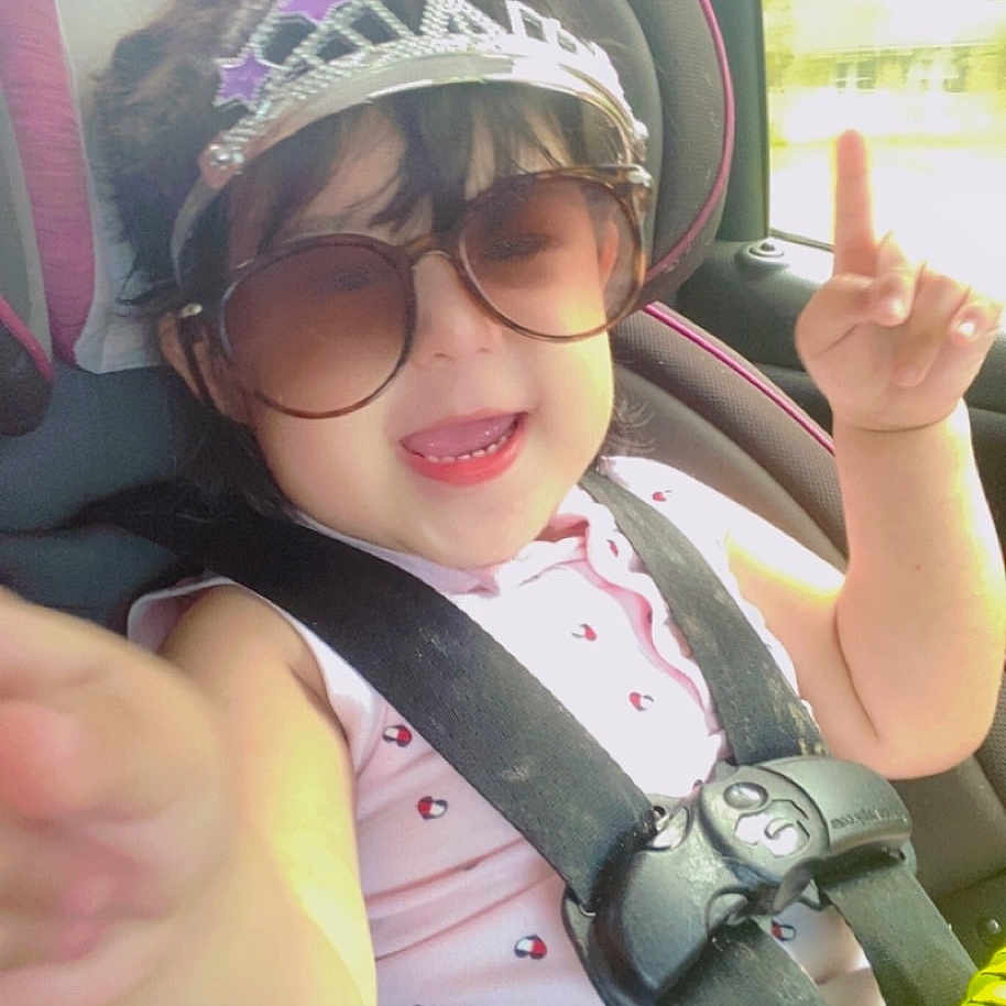 Neisly joined the competition — help win amazing prizes! accessory, baby, car_interior, car_seat, child, clothing, cute, daylight, face, fun, happy, person, pointing, seatbelt, sitting, smile, sunglasses, tiara, toddler, window