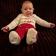 Gabin a rejoint le concours — aidez-le/la à gagner de superbes lots ! baby, child, infant, smiling, red_pants, white_socks, cream_shirt, sofa, brown_background, happy, sitting, indoors, cute, festive_clothing, portrait, young_child, cozy, small_hands, face, eyes