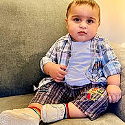 Muhammad Aahill is registered to the contest to win money with this photo: baby, toddler, child, plaid_shirt, white_tshirt, plaid_shorts, rainbow_socks, white_shoes, couch, indoor, seated, curious, chubby_cheeks, person, portrait, casual_clothing, comfortable, young_child, home, cute