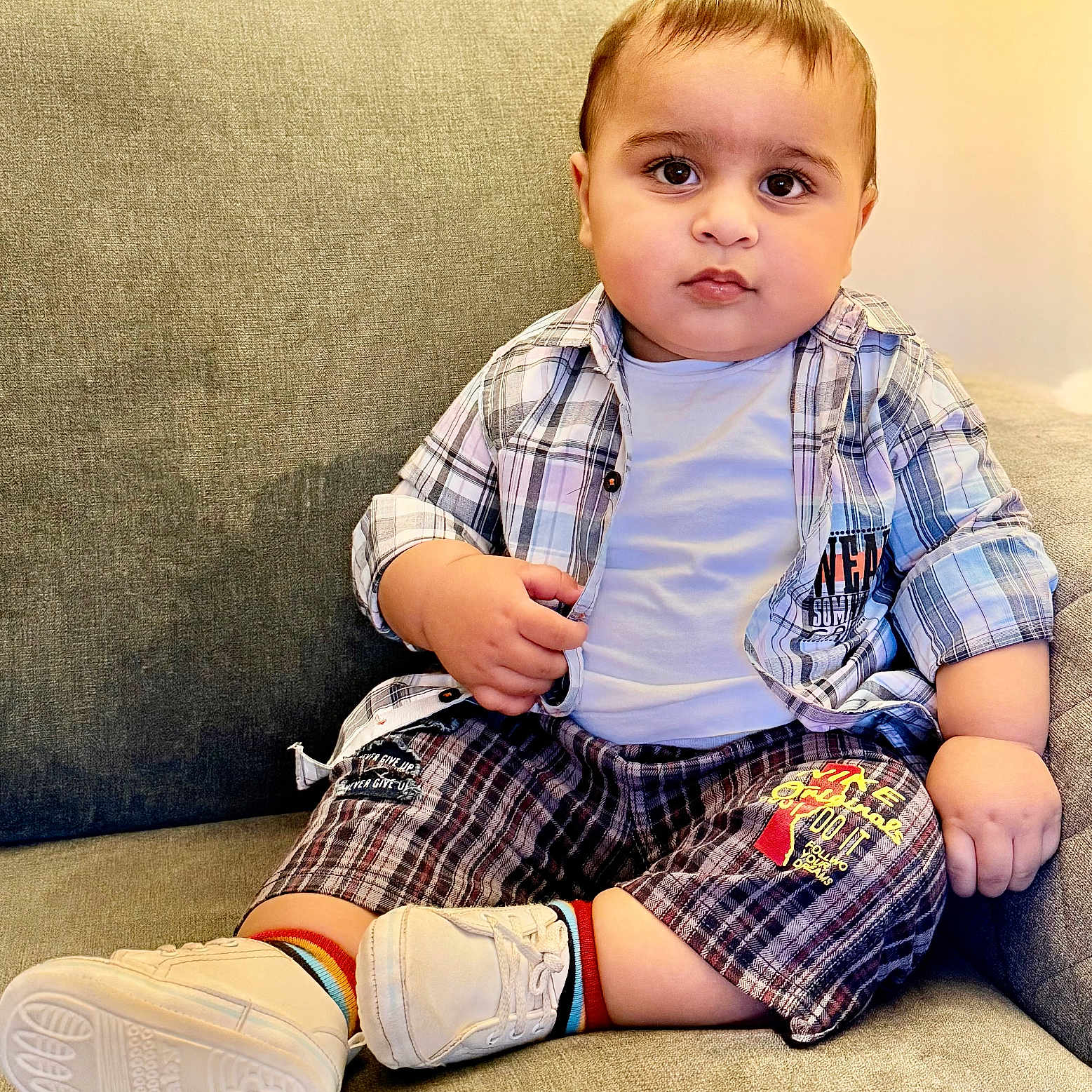 Muhammad Aahill is registered to the contest to win money with this photo: baby, casual_clothing, child, chubby_cheeks, comfortable, couch, curious, cute, home, indoor, person, plaid_shirt, plaid_shorts, portrait, rainbow_socks, seated, toddler, white_shoes, white_tshirt, young_child