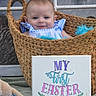 baby, basket, blue_clothing, child, cute, easter, easter_sign, face, festival, first_easter, front_view, happy, indoors, infant, plush_toy, portrait, sign, smile, woven_basket, young_child