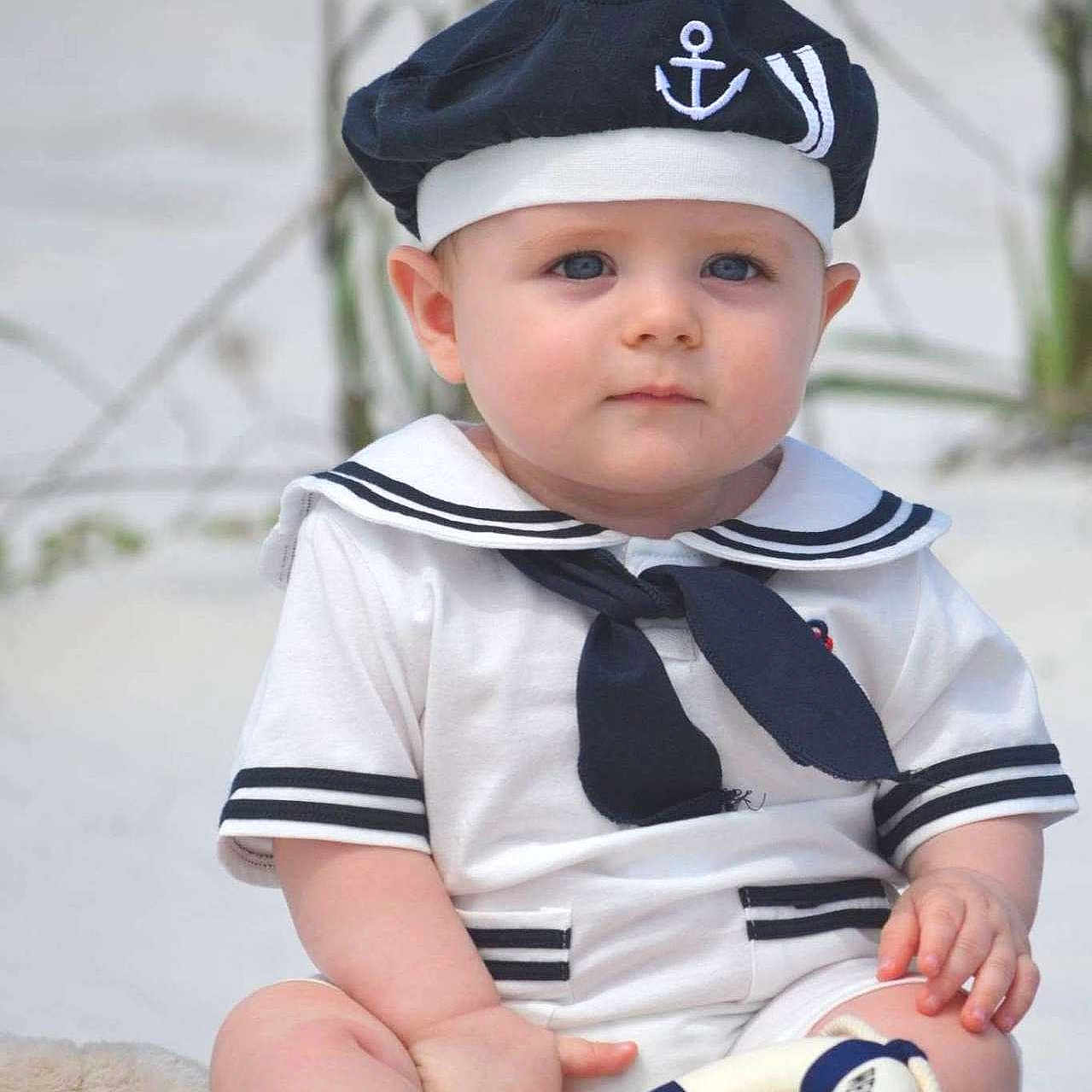Connor is registered to the contest to win money with this photo: baby, child, sailor_outfit, hat, blue_eyes, toy, life_preserver, sitting, outdoor, cute, portrait, clothing, infant, person, navy_theme, white_clothes, barefoot, summer, young_child, serious_expression