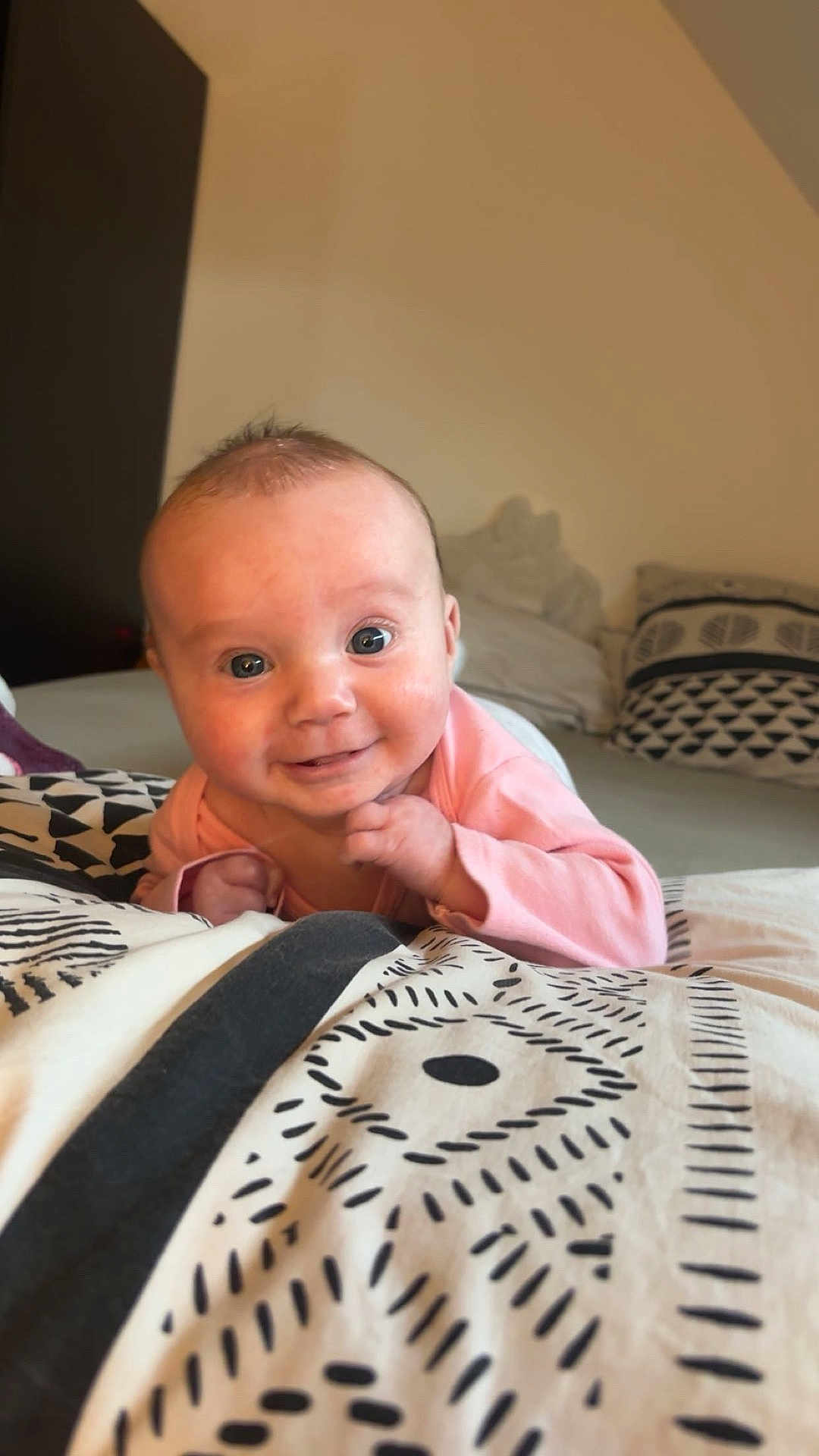 Maëlya a rejoint le concours — aidez-le/la à gagner de superbes lots ! baby, infant, smiling, pink_clothing, blanket, patterned_blanket, bedroom, pillow, face, happy, lying_down, cute, child, human, indoors, young_child, cheerful, cozy, soft_light, portrait