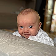 Maëlya participe au concours pour gagner de l'argent avec cette photo : baby, child, blue_eyes, smile, face, indoor, blanket, white_clothing, infant, cute, portrait, head, skin, young_child, toddler, expression, person, happy, soft_light, close_up
