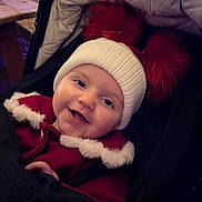 Heidi is registered to the contest to win money with this photo: baby, child, smiling, happy, hat, pom_poms, red_coat, fur_trim, stroller, face, winter_clothing, cute, portrait, infant, cozy, closeup, headwear, person, warm, outdoor