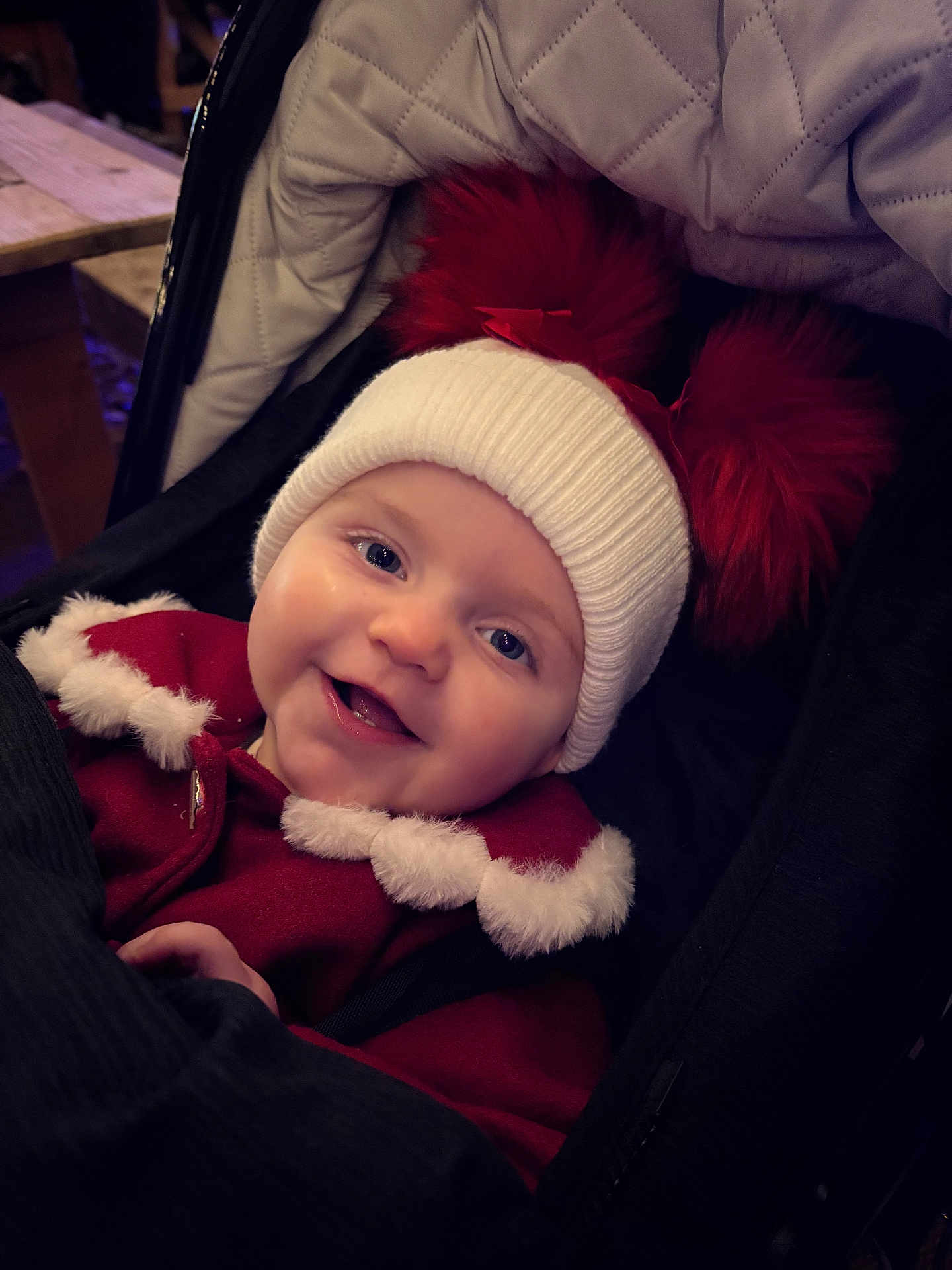 Heidi is registered to the contest to win money with this photo: baby, child, smiling, happy, hat, pom_poms, red_coat, fur_trim, stroller, face, winter_clothing, cute, portrait, infant, cozy, closeup, headwear, person, warm, outdoor