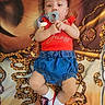 Kaliyah is registered to the contest to win money with this photo: baby, blue_shorts, child, clothing, colorful, comfort, cute, face_print, headband, indoor, infant, lying_down, pacifier, patterned_blanket, portrait, red_clothing, shoes, small_hands, socks, young_child