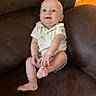 baby, ball, barefoot, child, clothing, couch, expression, face, floor, foot, furniture, hand, home, indoor, infant, shirt, shorts, sitting, skin, toy