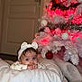 baby, infant, headband, bow, blanket, christmas_tree, ornament, red_lights, white_tree, holiday, festive, indoor, door, bokeh, cozy, soft_texture, portrait, blue_eyes, cheeks, lying_down