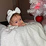 Léonie participe au concours pour gagner de l'argent avec cette photo : baby, infant, headband, bow, white_blanket, blanket, christmas_tree, ornament, red_ornament, holiday, decorations, face, eyes, hands, cozy, soft_texture, indoors, portrait, bokeh, curious