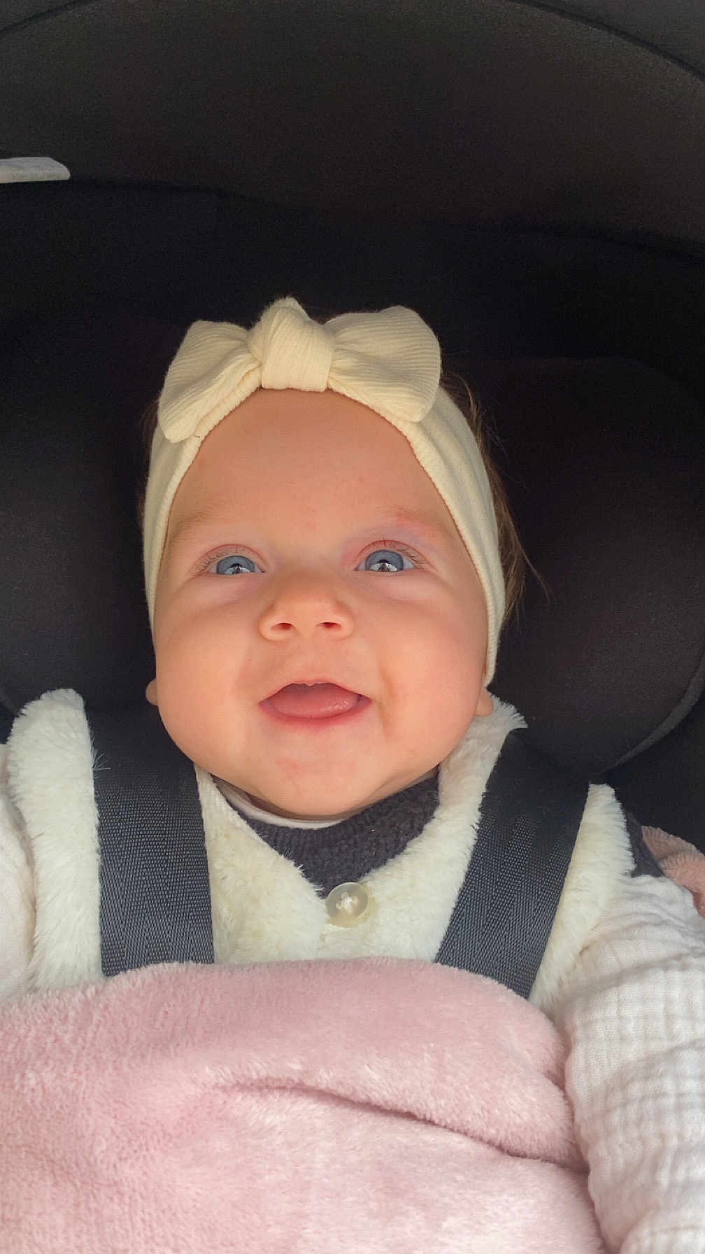 Léonie participe au concours pour gagner de l'argent avec cette photo : baby, infant, child, car_seat, headband, bow, blanket, smile, blue_eyes, cheeks, face, clothing, strap, buckle, close_up, portrait, soft_texture, happy, seat, warm