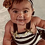 baby, smiling, headband, gold_bow, striped_outfit, chubby_cheeks, sitting, cute, happy, portrait, infant, child, face, skin, eyes, mouth, arms, legs, white_background, clothing