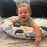 baby, blanket, carpet, child, clothing, curly_hair, cushion, cute, face, happy, home, indoor, infant, living_room, person, pointing, smiling, sofa, toddler, whale_pattern
