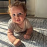 arm, baby, carpet, child, clothing, crawling, curly_hair, cute, expression, face, floor, home, indoor, light_and_shadow, person, portrait, smile, sunlight, toddler, young_child