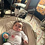 baby, infant, cat, chair, baby_seat, onesie, toy, curly_hair, indoor, carpet, furniture, pet, animal, cute, relaxed, home, cozy, portrait, child, smiling