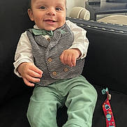 Jayvon joined the competition — help win amazing prizes! baby, child, smiling, sitting, clothing, vest, bow_tie, green_pants, white_shirt, couch, black_couch, toy, colorful_toy, face, happy, indoors, television, furniture, person, portrait