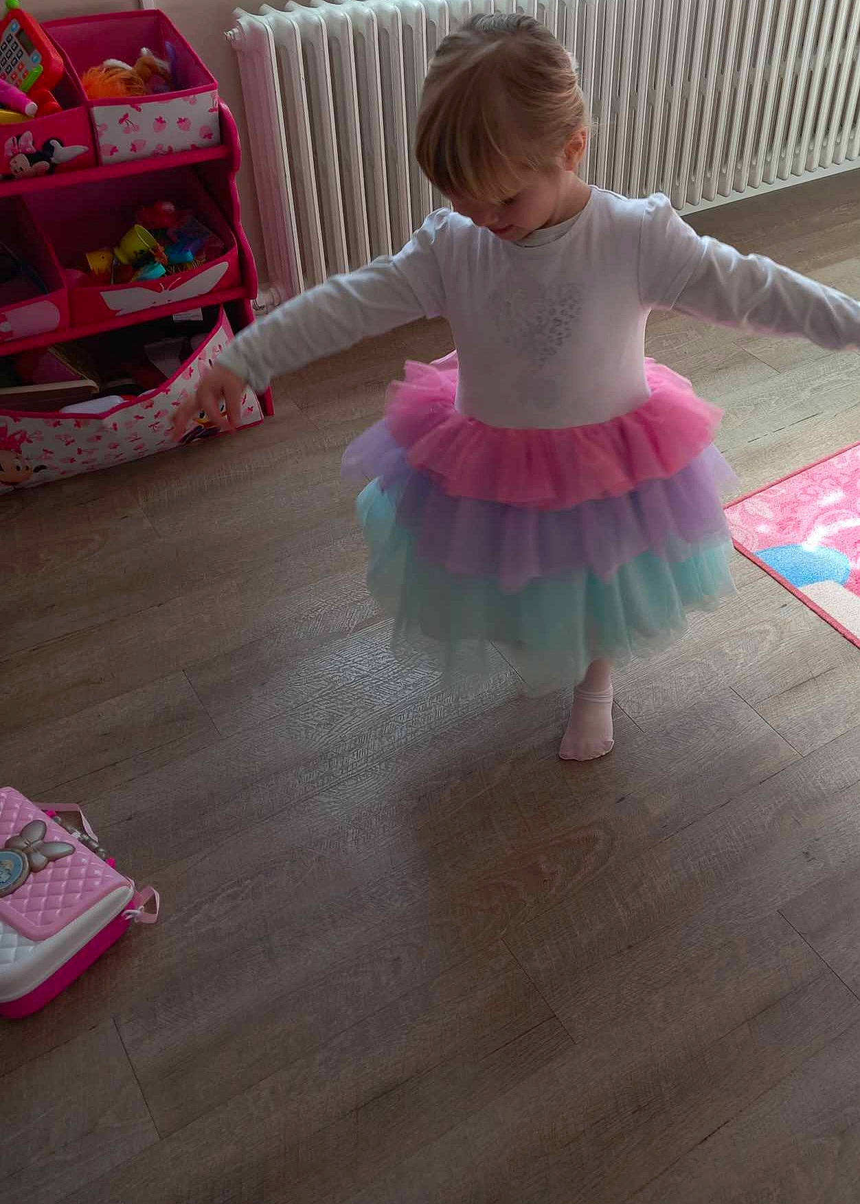 Emma a rejoint le concours — aidez-le/la à gagner de superbes lots ! baby, baby_toddler_clothing, ballet_tutu, barefoot, child, entertainment, flooring, fun, hardwood, human_leg, magenta, pattern, person, pink, play, product, sleeve, textile, toddler, wood