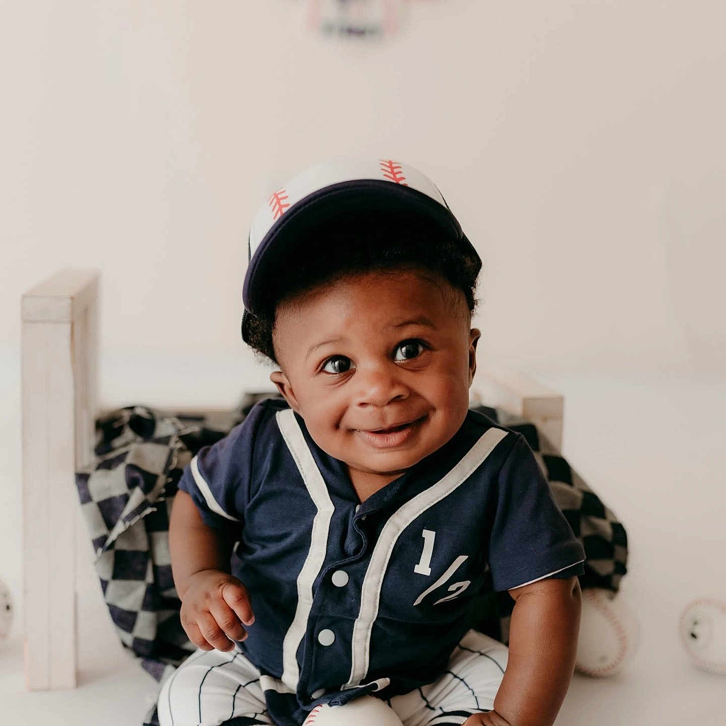 Caleb joined the competition — help win amazing prizes! baby, child, baseball, cap, smile, sportswear, blue_clothing, striped_pants, socks, sitting, indoor, toy, soft_lighting, portrait, cute, decorations, tassels, happy, person, infant