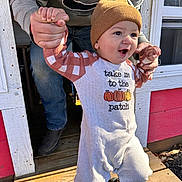 Jack is registered to the contest to win money with this photo: toddler, child, beanie, onesie, pumpkin, hands, adult, support, porch, wood, sunlight, outdoor, smile, walking, clothing, footwear, door, jeans, sweatshirt, happy