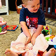 Colt joined the competition — help win amazing prizes! toddler, child, smiling, playing, blanket, stuffed_animal, toy, carpet, indoor, crib, basket, clothing, happy, barefoot, curly_hair, person, room, furniture, floor, baby