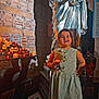 child, candle, statue, church, chapel, lighting, shadow, dress, floor, wall, plaque, shoes, person, indoor, religious, smile, holding, decor, flicker, young