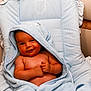 baby, smiling, towel, blue_towel, hooded_towel, infant, cushion, striped, seat, upholstery, comfortable, relaxed, skin, baby_skin, baby_face, baby_hands, indoors, portrait, child, cute