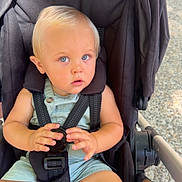Dario participe au concours pour gagner de l'argent avec cette photo : toddler, child, stroller, baby, blue_eyes, blond_hair, outdoor, sunlight, seatbelt, curious, hands, feet, clothing, person, wheels, black_fabric, safety_harness, expression, closeup, portrait