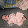 baby, infant, pink_clothing, polka_dots, blanket, bed, lying_down, blue_eyes, indoor, soft_toys, baby_gear, curious, cute, child, newborn, sleeping_area, foot, hand, face, resting