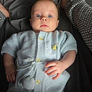 Amina Isla joined the competition — help win amazing prizes! baby, infant, knitted_clothing, blue, blanket, bed, human_hand, person, adult_leg, patterned_pants, curious_expression, indoor, portrait, soft_lighting, cozy, cute, newborn, lying_down, closeup, child