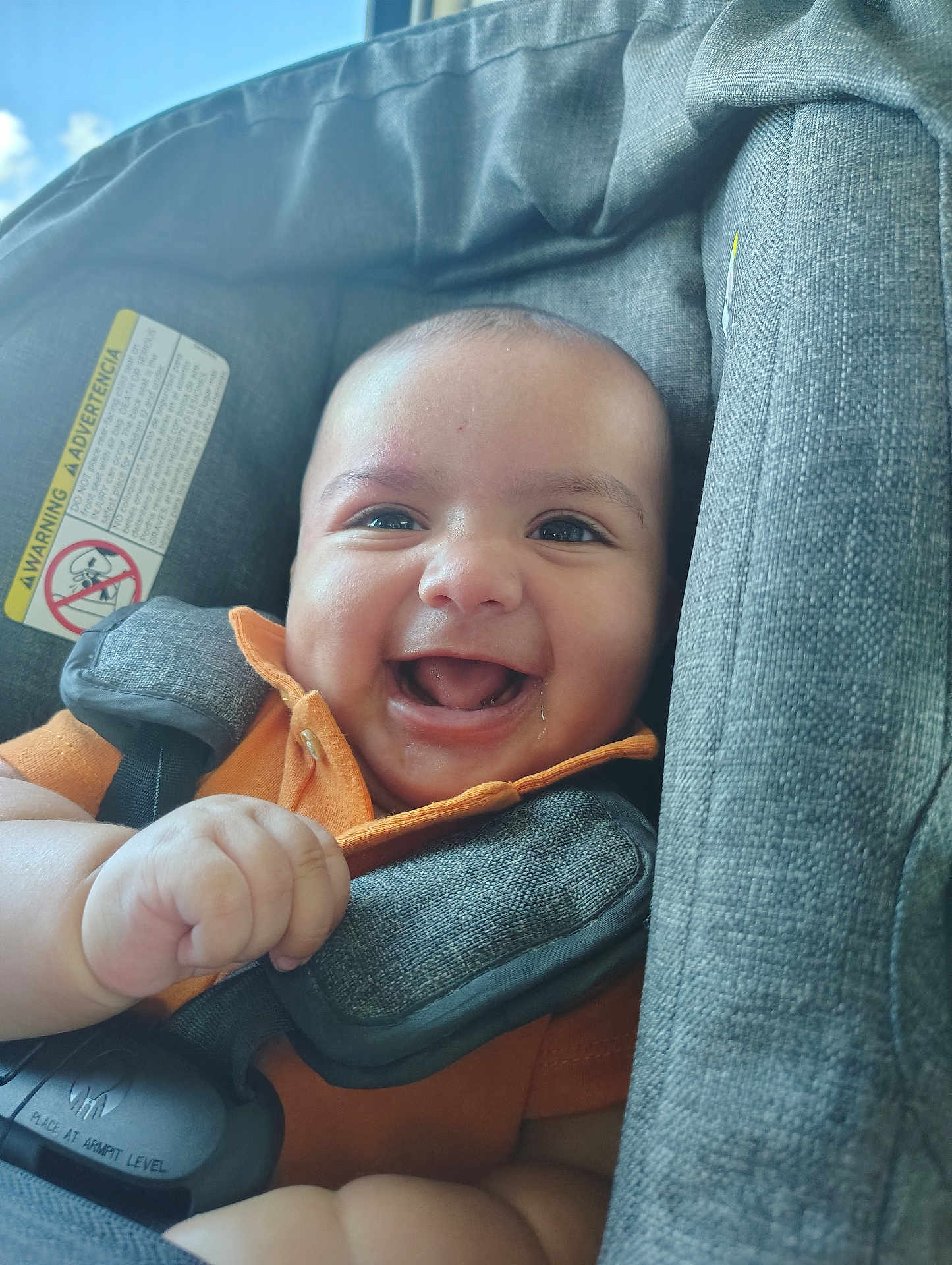 Ezekiel joined the competition — help win amazing prizes! baby, smiling, car_seat, child, orange_shirt, happy, infant, portrait, face, seatbelt, child_safety, cute, indoors, person, skin, hand, young_child, seat, closeup, bright