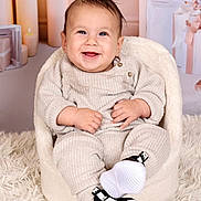 Naïm participe au concours pour gagner de l'argent avec cette photo : baby, child, smiling, knitwear, shoes, nike, chair, fluffy_rug, candles, gift_boxes, indoors, portrait, cute, happy, cozy, infant, sitting, fashion, warm, soft_lighting