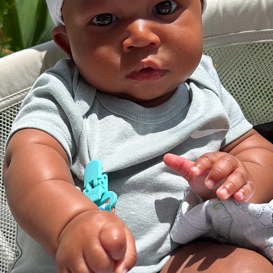 Chozyen is registered to the contest to win money with this photo: baby, baby_chair, child, chubby, closeup, cloth_clip, curious, daylight, greenery, hands, hat, house, infant, legs, onesie, outdoor, portrait, skin, sunlight, white_hat