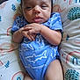 Christopher is registered to the contest to win money with this photo: baby, infant, blue_onesie, shark_pattern, pillow, rainbow_pattern, leaf_pattern, hands, face, eyes, mouth, skin, person, lying_down, indoors, cute, child, newborn, comfort, clothing
