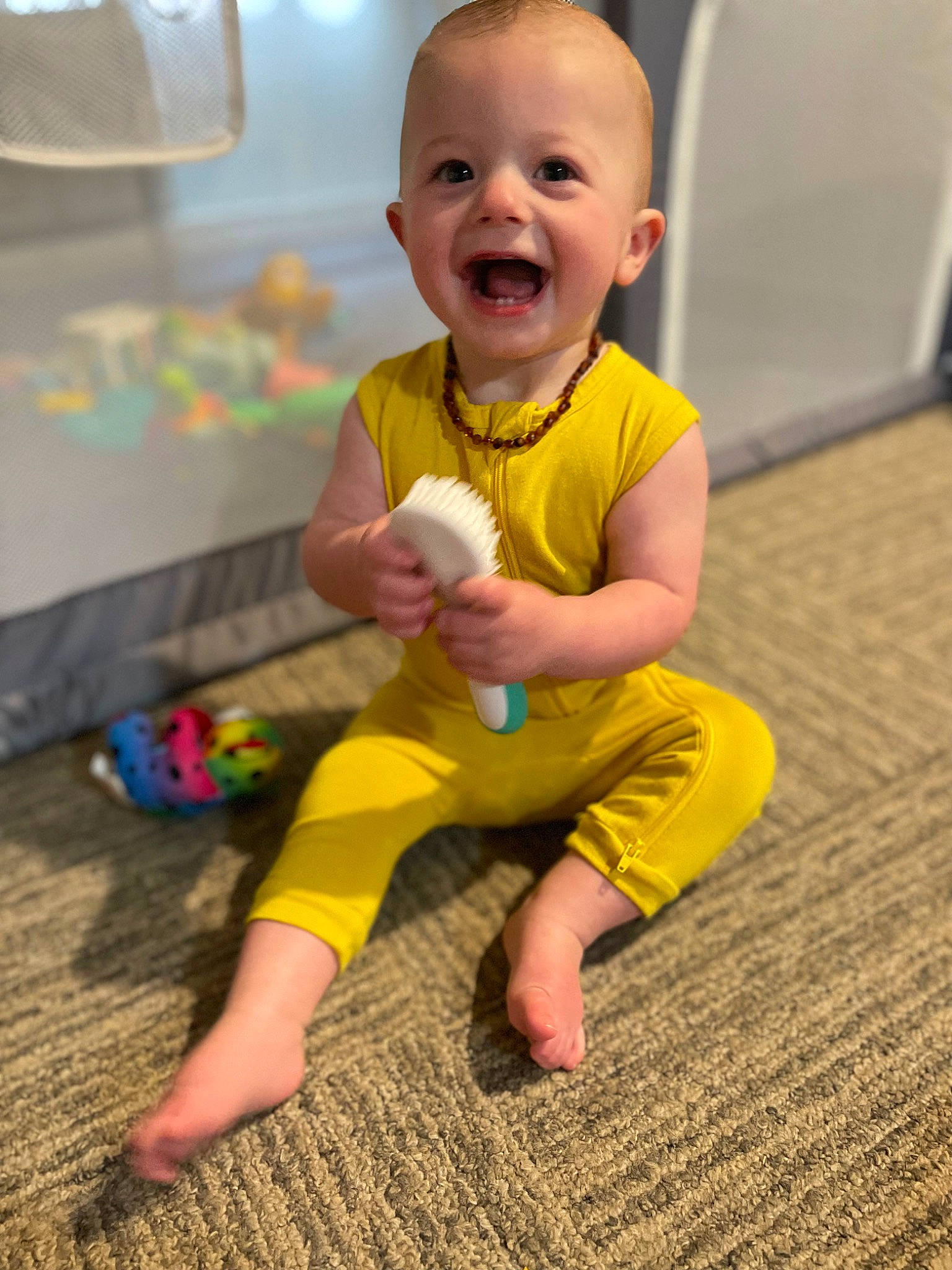 Everett is registered to the contest to win money with this photo: baby, baby_toddler_clothing, barefoot, child, eye, face, floor, flooring, foot, fun, happy, human_leg, joint, knee, person, sitting, skin, smile, standing, toddler