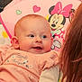 baby, infant, woman, face, smile, clothing, glasses, person, child, indoor, colorful, pattern, polka_dot, cartoon, minnie_mouse, pink, cute, happy, apparel, portrait