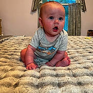 Grayson is registered to the contest to win money with this photo: baby, bed, blanket, blue_eyes, child, clothing, curtains, expression, feet, flooring, gray_shirt, hands, head, indoor, infant, person, room, skin, soft_texture, window