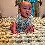 baby, infant, blanket, bed, curtains, window, indoor, person, child, expression, clothing, gray_shirt, flooring, room, soft_texture, hands, feet, skin, head, blue_eyes