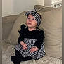 baby, child, infant, couch, pillow, headband, black_and_white, houndstooth, clothing, sitting, indoor, curious, cute, furniture, soft, blanket, person, portrait, young_child, cozy