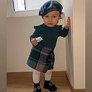 Keyna participe au concours pour gagner de l'argent avec cette photo : beret, black_shoes, bow, child, clothing, cute, fashion, flower, indoor, natural_light, person, plaid_skirt, portrait, standing, text_overlay, toddler, wall, white_tights, window, wooden_floor